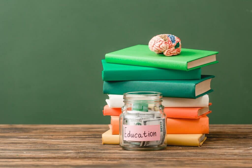 books, piggy bank and brain on wooden surface isolated on green
